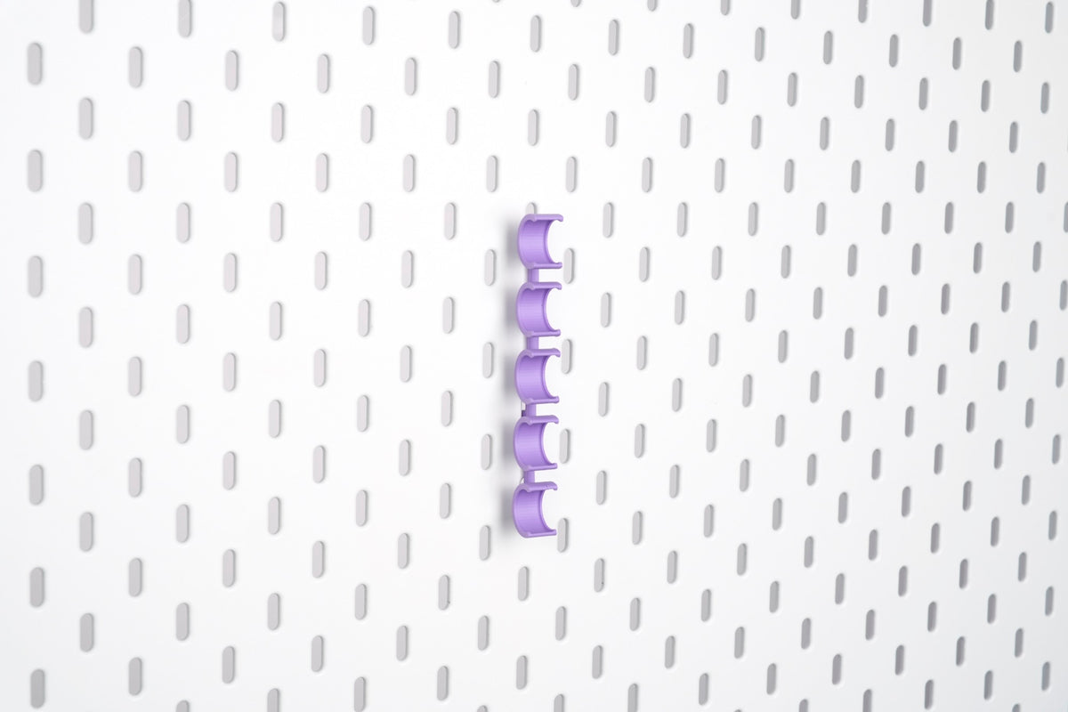 Empty violet purple pegboard bobbin holder set with five vertical clips for sewing bobbins