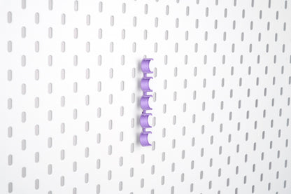 Empty violet purple pegboard bobbin holder set with five vertical clips for sewing bobbins
