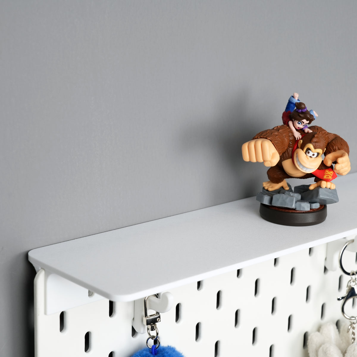 White top shelf mounted above an IKEA SKÅDIS pegboard with utility hooks beneath