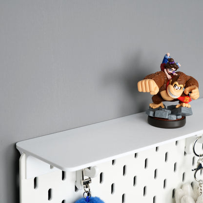 White top shelf mounted above an IKEA SKÅDIS pegboard with utility hooks beneath