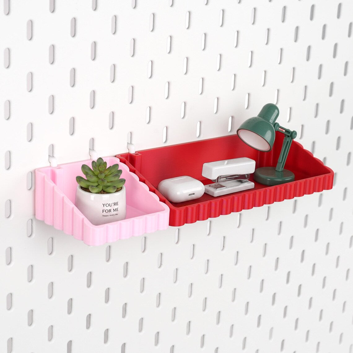 Pink and red wave pegboard storage shelves holding small desk accessories
